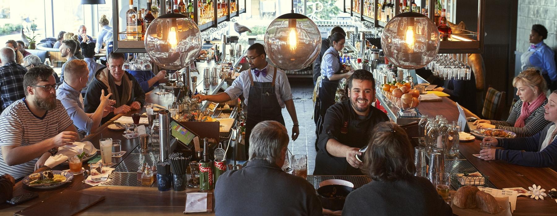 a group of people sitting at a restaurant bar with food